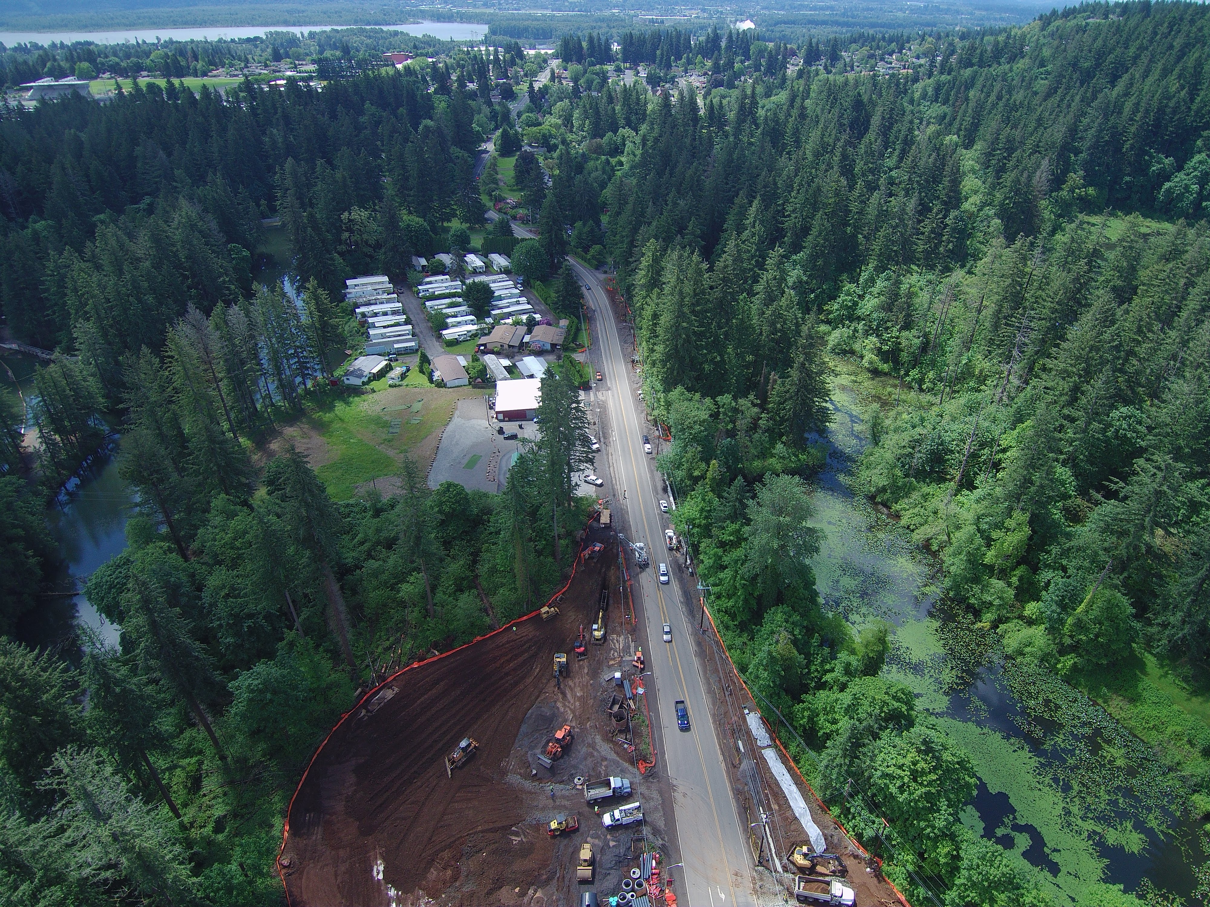 Drone photography of a roundabout construction site in a forest, with the Columbia River in the background.